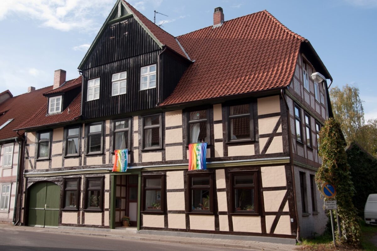 Altes Fachwerkhaus mit zwei Peace-Flaggen in Regenbogenfarben, die aus den Fenstern hängen