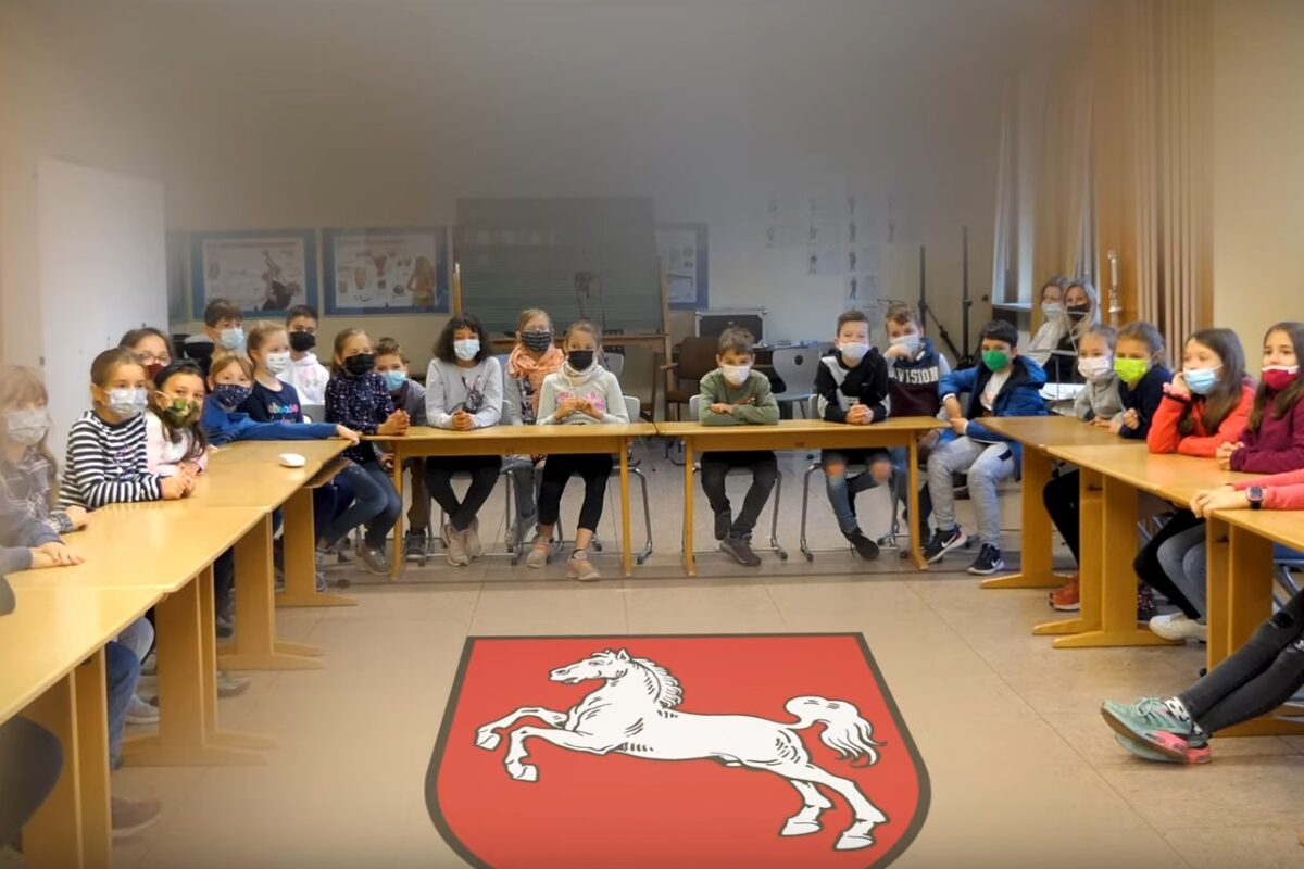 Klasse im Klassenraum, niedersächsisches Wappen am Boden