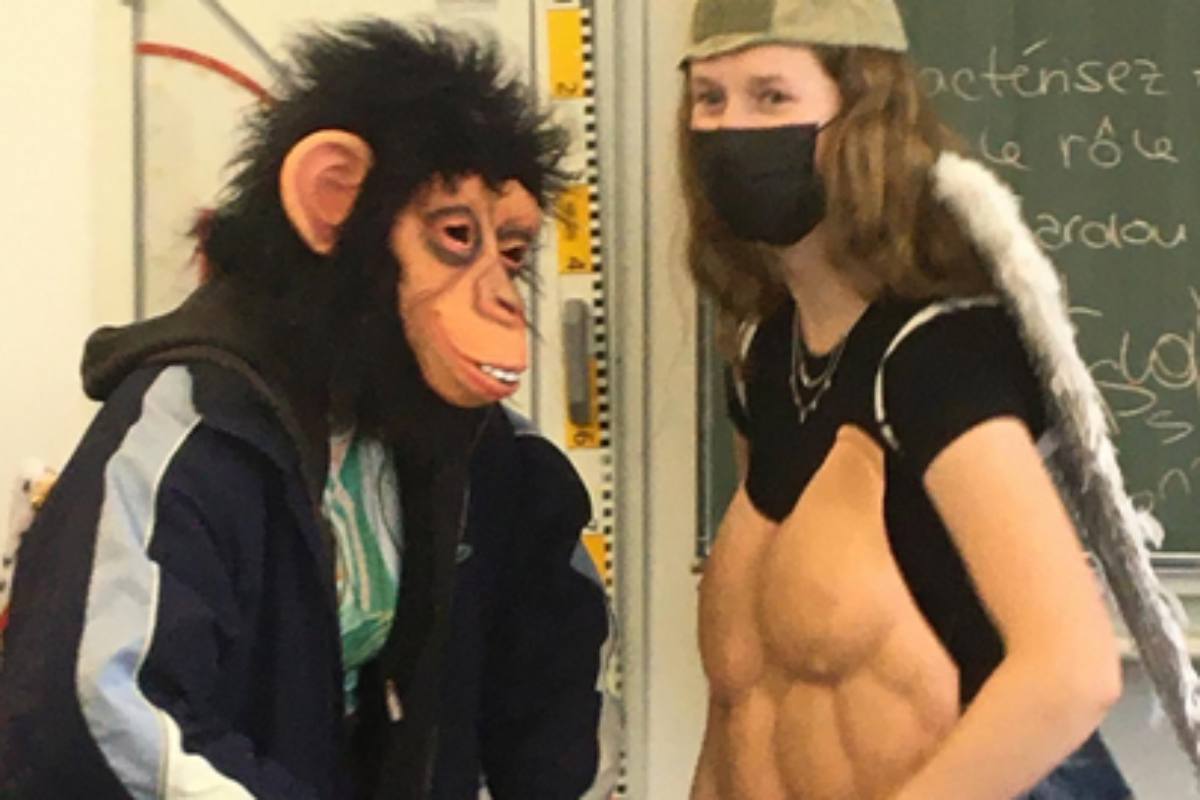 Zwei Schüler:innen agieren in Verkleidung mit Affenmaske und Panzerbrust